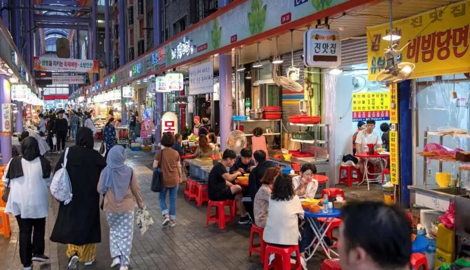 充滿活力的釜山富平罐頭夜市景象，遊客於燈光璀璨街道上穿梭，品嚐各種韓國街頭美食，感受市場熱鬧氛圍。