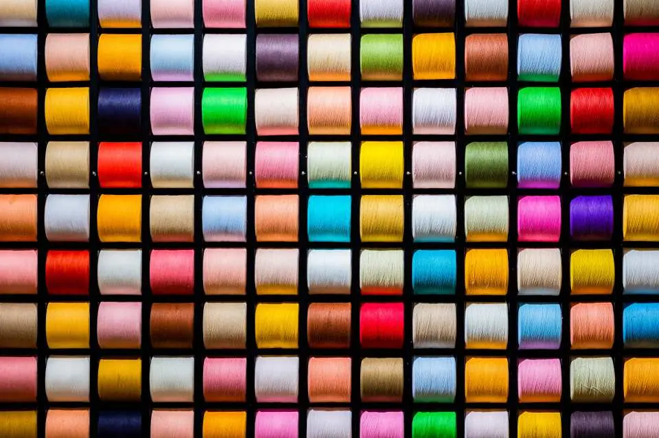A close-up view of the Imabari Towel Museum's wall display, featuring hundreds of vibrantly colored yarn spools meticulously arranged, showcasing the rich hues and detailed aesthetics of textile craftsmanship.