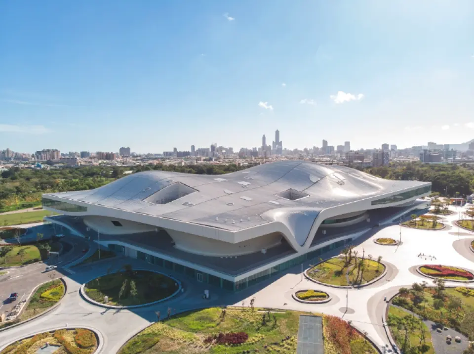 Aerial view of the stunning Weiwuying National Kaohsiung Center for the Arts during daytime, showcasing its unique banyan-inspired architecture and surrounding green landscape under a blue sky, a cultural landmark in Kaohsiung.