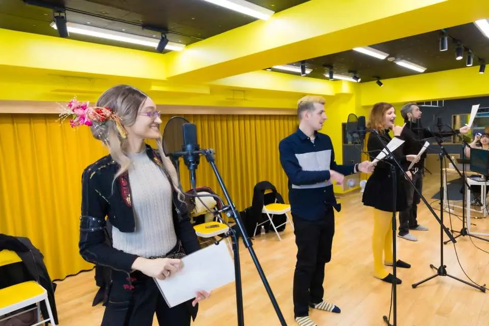 A participant in the Tokyo Ikebukuro recording studio enthusiastically performs voice acting into a professional microphone, showcasing passion and vocal potential.