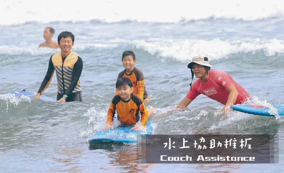 A professional coach assists a child on a surfboard in the waters of Yilan's Wushigang, providing water assistance and making learning to surf enjoyable for kids.