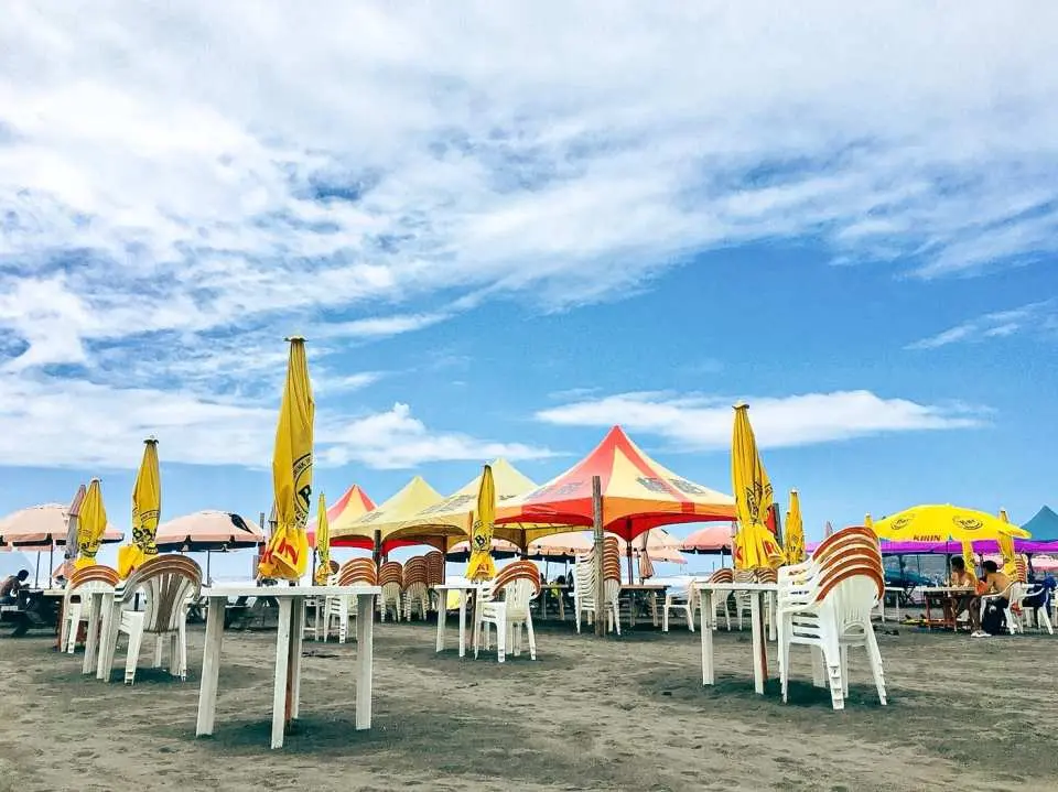 A vibrant relaxation area at Yilan's Wushigang North Embankment Beach, featuring numerous colorful parasols, tables, and chairs, offering a comfortable space for visitors to unwind after surfing.