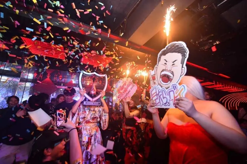 日本夜店內歡樂派對場景，人們手持趣味道具，彩帶和仙女棒齊飛，盡享熱鬧非凡的日本夜生活。