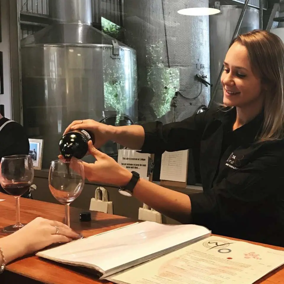 A staff member pouring red wine during a guided tasting at a Tamborine Mountain winery, offering visitors a chance to savor Queensland's finest selections.