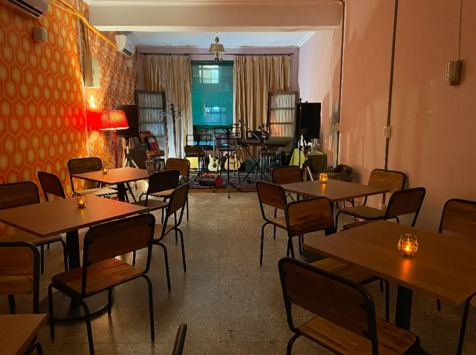 The empty retro Hong Kong-style cafe in Taipei's Dadaocheng, set up for the Open Mic event with a stage and inviting seating, ready for a night of music and socializing.