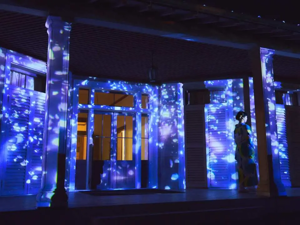 【フォトジェニック・ウォールアート・プロジェクション~儚くひかる蝶の散華（さんげ）】演出のテーマは「ピンカートンと息子との別れ」、そして「蝶々夫人の名誉のための最後」。蝶が花びらになって儚く散りゆくプロジェクションマッピング映像で表現した作品です。芝生エリアから眺めて楽しむ、プロジェクション映像に入り込み写真を撮るといった楽しみ方もできます。