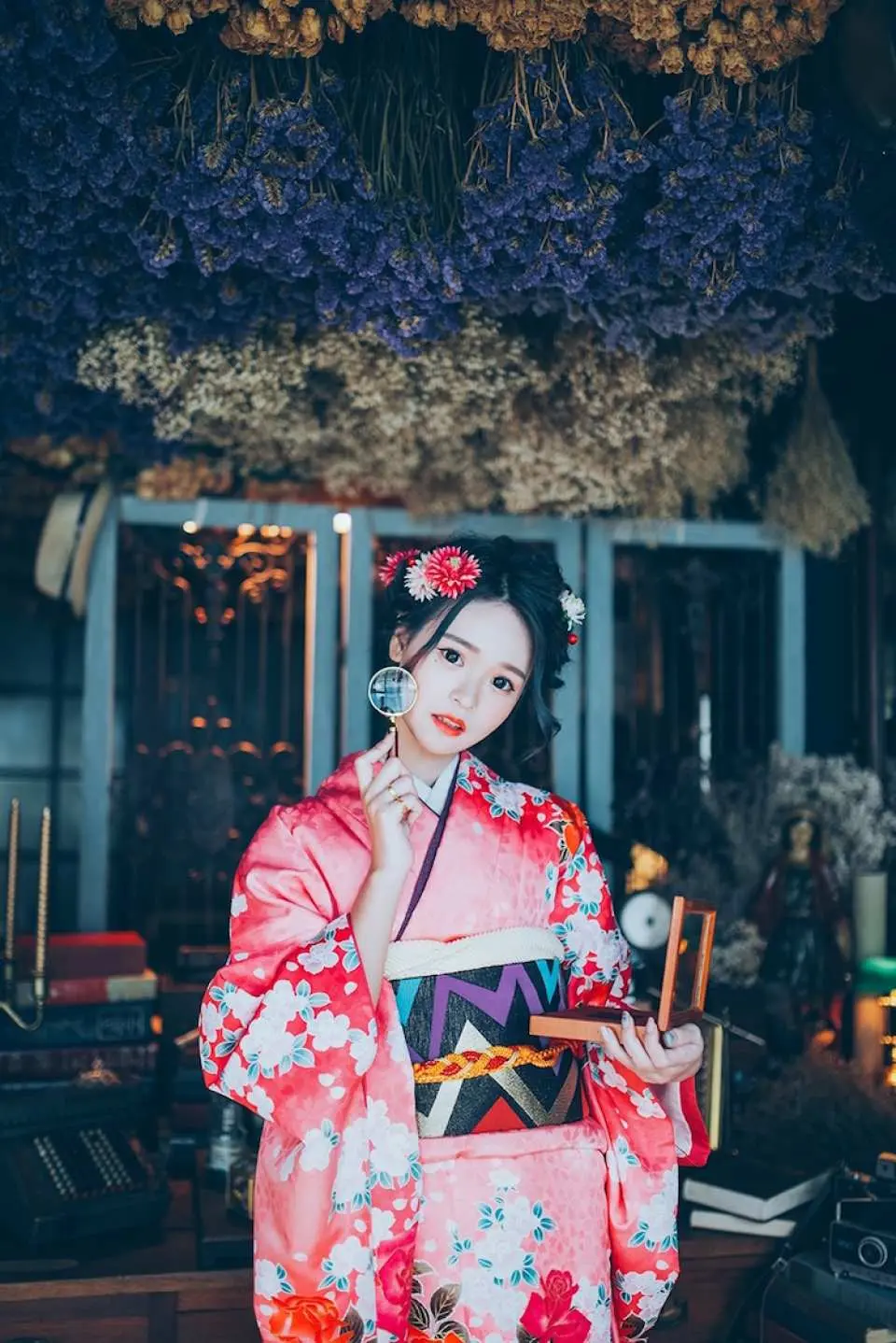 板橋優花梨和服租借體驗，女子身穿粉色系和服，手持團扇，在佈滿垂吊花飾的典雅室內空間留影。