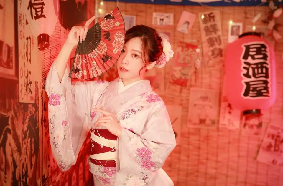 板橋優花梨和服租借，女子穿著清新花紋和服，手持扇子，在日式居酒屋風格背景下，體驗文化風情。