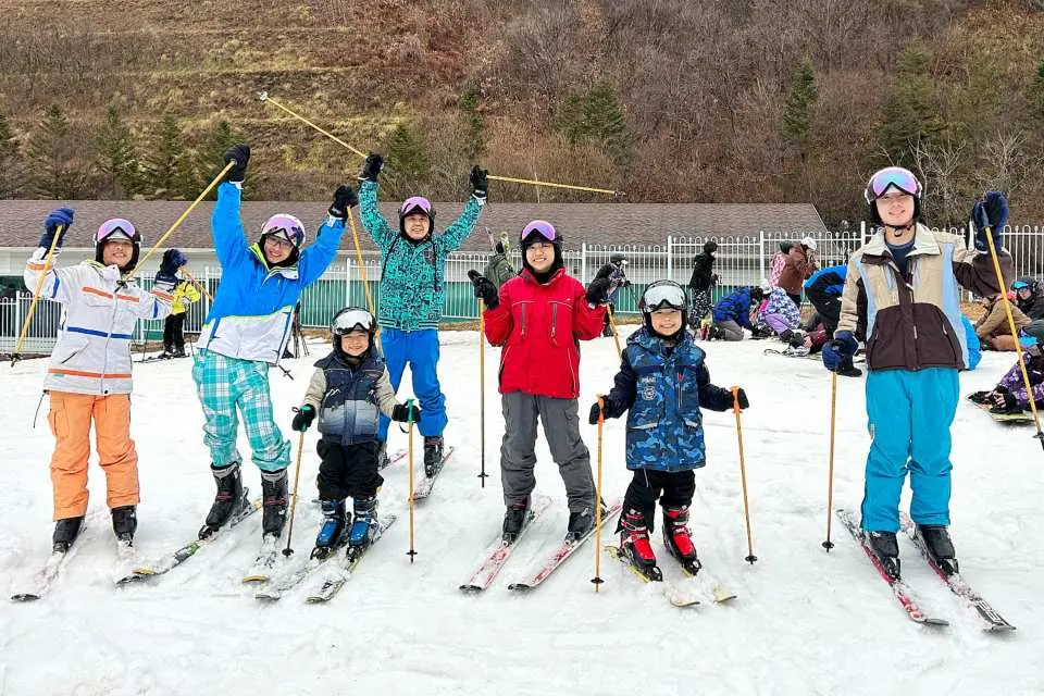 A joyful group of adults and children learning double-board skiing, enjoying their private instructor lesson at Elysian Gangchon Ski Resort in Korea.