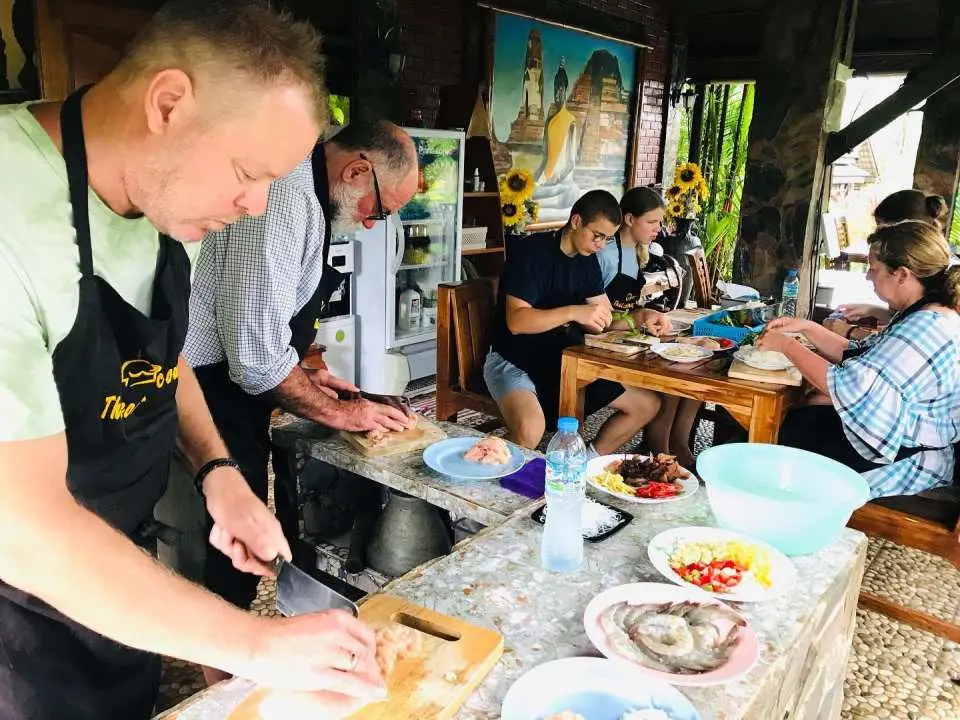 Khao Lak half-day cooking experience where participants, guided by a professional chef, focus on chopping and preparing fresh ingredients for Thai signature dishes.