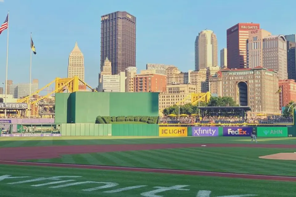 Field-level view of PNC Park's outfield, showcasing the vibrant green grass and the majestic Pittsburgh city skyline, ready for an exciting MLB Pittsburgh Pirates game.