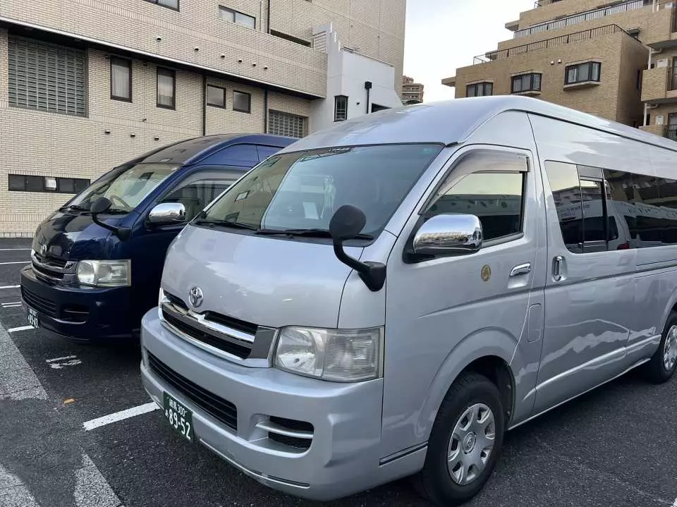 關西機場接送服務的兩種專屬車款，銀色與深藍色廂型車並排，滿足不同團體人數的出行需求，提供多樣化的選擇。