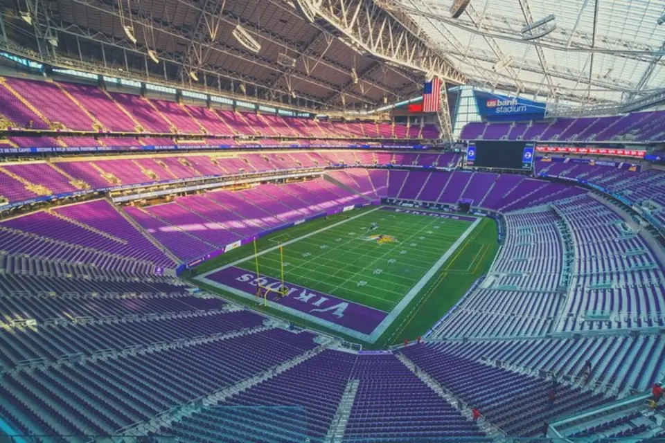 Panoramic interior view of US Bank Stadium, with sunlight illuminating the vast purple seating areas, showcasing the modern architectural design and grandeur of the Minnesota Vikings' home ground, ready for an NFL game.