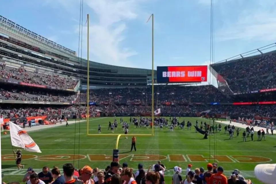 芝加哥士兵球场内，美式足球赛事结束，大屏幕显示“BEARS WIN”胜利时刻，球员与球迷共同庆祝芝加哥熊队的精彩胜利。