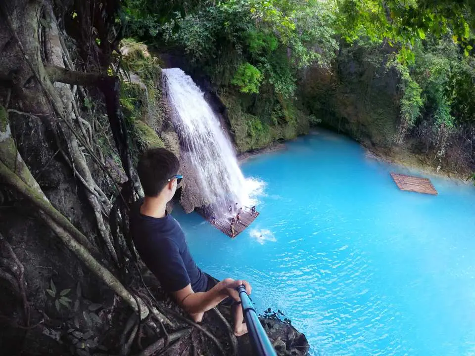 A tourist takes a selfie at the edge of Kawasan Falls' turquoise pool, capturing the excitement and stunning scenery of a Cebu canyoneering adventure.