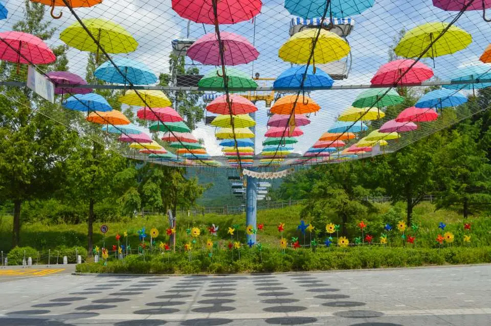 首爾大公園內色彩繽紛的傘海裝置藝術，點綴著花朵造型裝飾，營造歡樂氣氛。