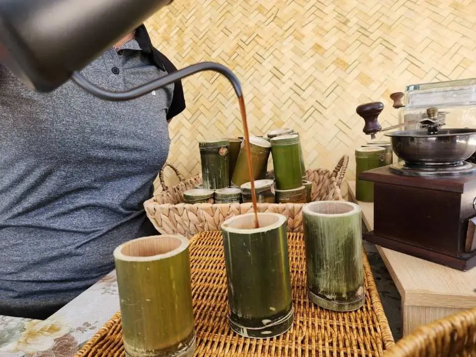 A staff member pours fresh coffee into natural bamboo cups, part of the delicious snacks and refreshing drinks offered during the exciting Phuket ATV jungle tour.