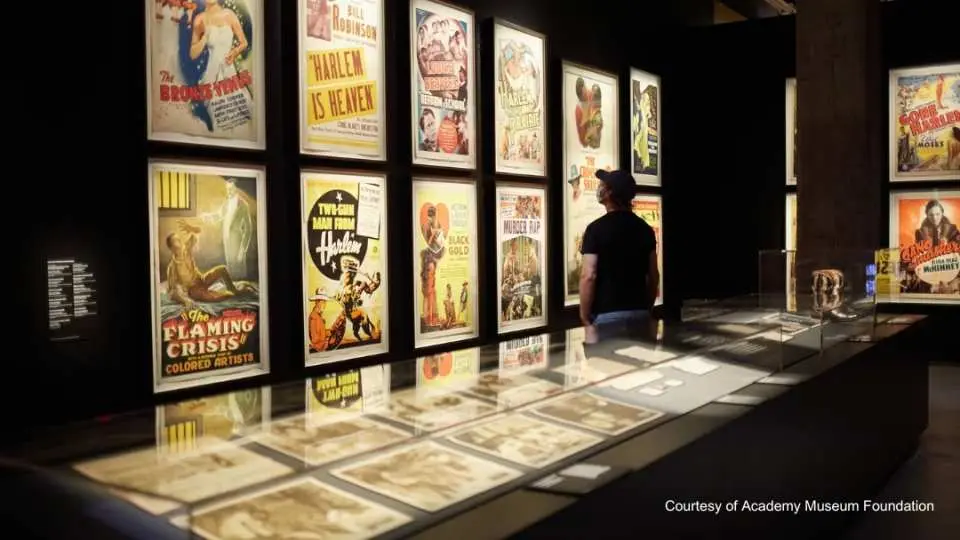 オスカー映画博物館に展示されたヴィンテージ映画ポスターの壁。古典映画の視覚芸術が表現され、手前には関連する遺物が展示されたショーケースがあります。