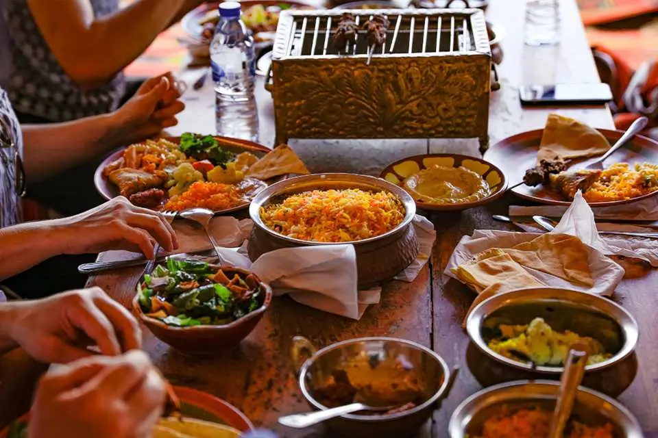 杜拜Al Khayma沙漠營地過夜探險的豐盛燒烤晚餐，桌上擺滿了多樣化的中東特色美食，供遊客大快朵頤。