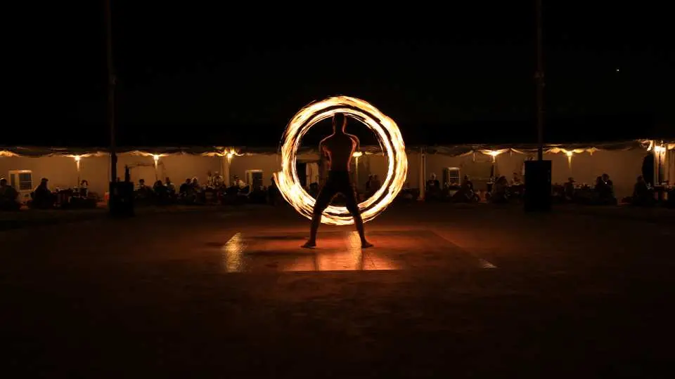 Al Khayma沙漠營地過夜探險中的精彩火舞表演，舞者在夜色中揮舞火焰，為賓客帶來視覺震撼。
