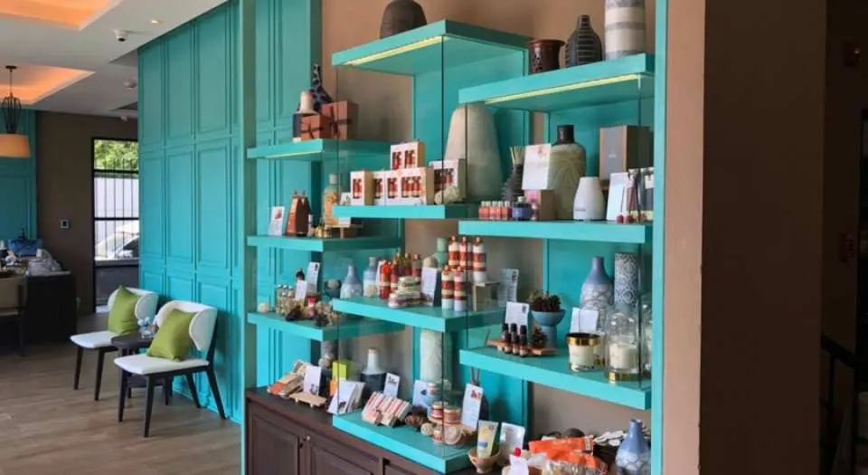 泰國華欣Let's Relax Spa的產品展示區，碧藍色層架上陳列著各種芳香精油、身體乳液和水療用品，供顧客選購泰式按摩相關產品。