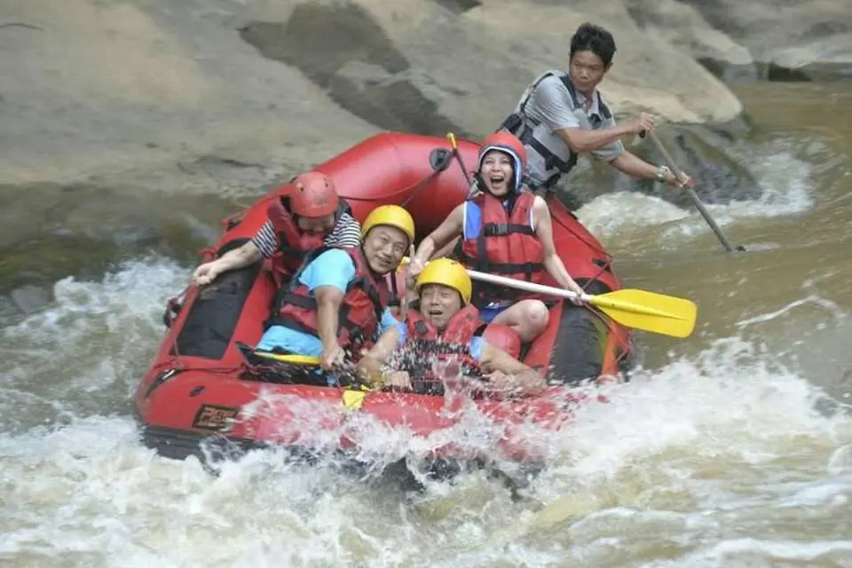 Thrilled tourists white water rafting on Mae Taeng River in Chiang Mai, paddling energetically through splashing rapids during an exciting half-day adventure.