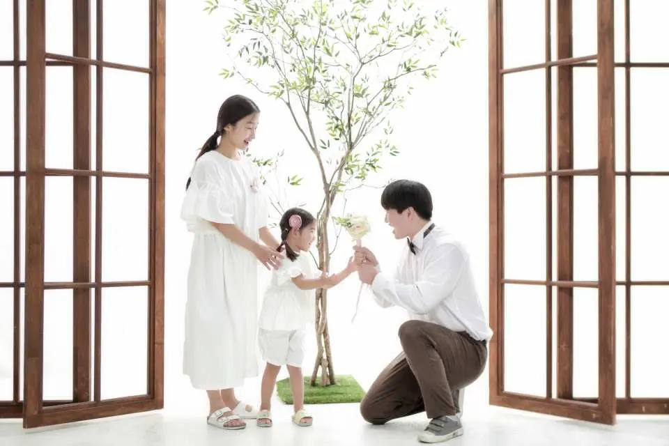韓國首爾Z-and室內攝影棚，身著休閒服飾的父母親與可愛女兒，在綠意盎然的樹木背景前拍攝溫馨親密的家庭合影。