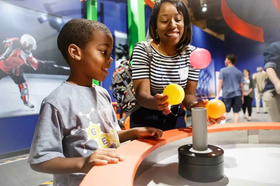 A mother and son happily interact with colorful science exhibits at the Children's Museum of Atlanta, sparking curiosity through playful, hands-on learning experiences.