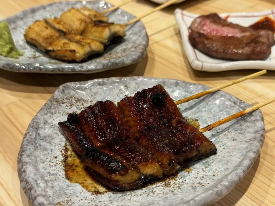 蓬鬆香的烤鰻魚串真是太精緻了！蒲燒的味道甜、辣、多汁、酥脆♪我們有優雅的白烤版本，還有鑑賞家的烤肝臟。或是在上面放上蒲燒串也很適合鰻魚蓋飯◎。