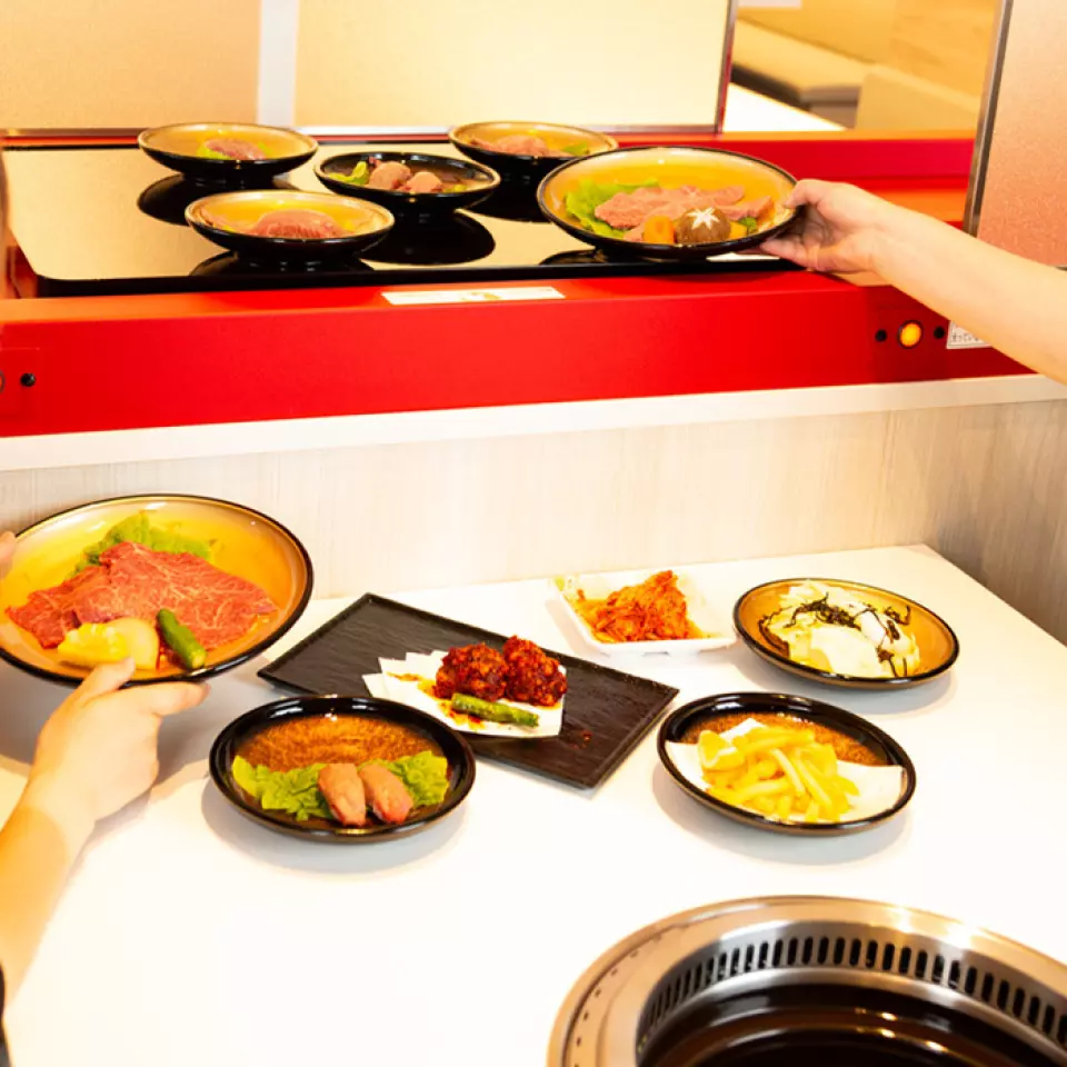 在以白色為基調的巷子烤肉座位上，肉是通過傳送帶壽司風格的“巷子”運送的。即使是有小孩的家庭也能享受到美味的肉。