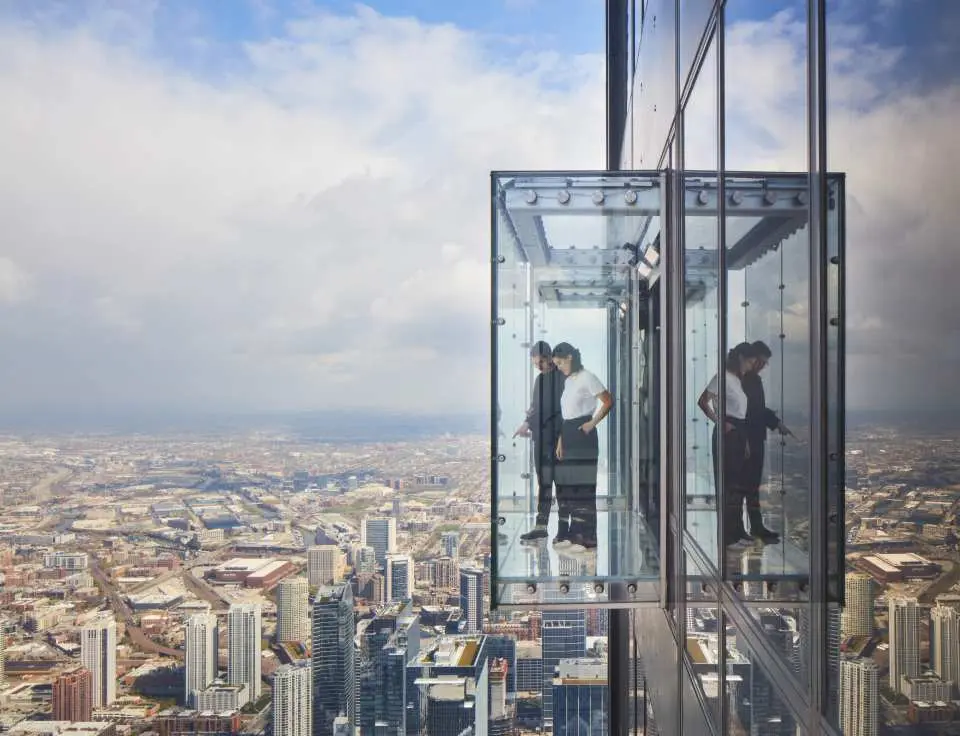 Visitors experience the thrilling transparent glass boxes of The Ledge at Skydeck Chicago, marveling at the boundless Chicago cityscape stretching to the horizon.