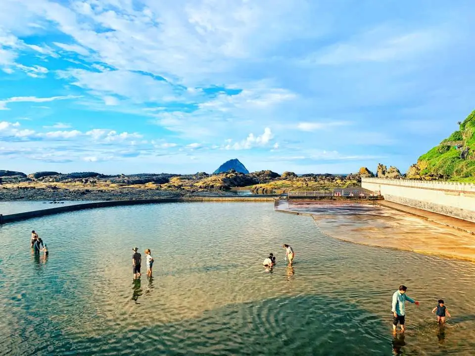 和平島地質公園的天然海水池，遊客們在碧藍池水中盡情戲水，感受大自然的沁涼與樂趣。