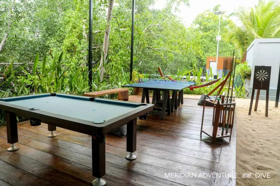 Meridian Adventure Dive Resort's outdoor game area, featuring a billiard table and foosball, offering guests endless entertainment amidst tropical scenery.
