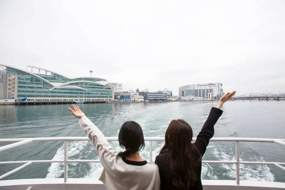Hai du khách trên boong du thuyền Jagalchi Busan hướng về phía đường chân trời của cảng Busan, tận hưởng chuyến tham quan biển tuyệt đẹp.