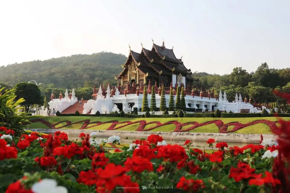 Majestic Thai temple architecture in Chiang Mai's Royal Park Rajapruek, with golden roofs contrasting red flowers and green landscapes, a classic attraction included in the pass.