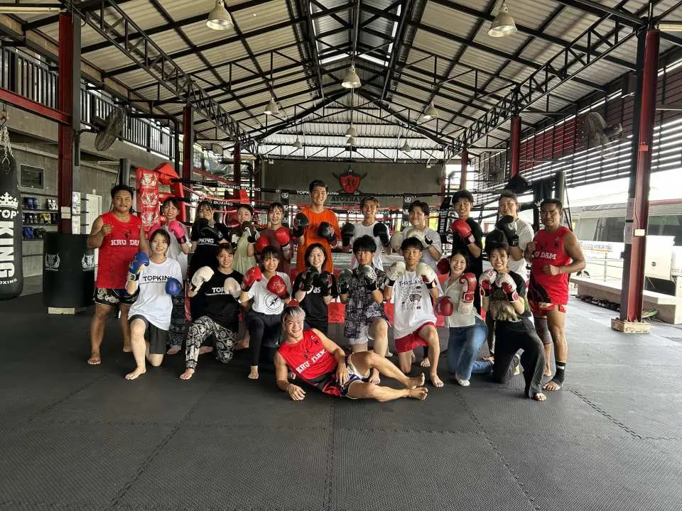 アユタヤのTopKing Krudam Ayothaya Fight Gymで、熱心な参加者たちがボクシンググローブを着用し、充実したムエタイクラスの後に記念写真を撮影しています。
