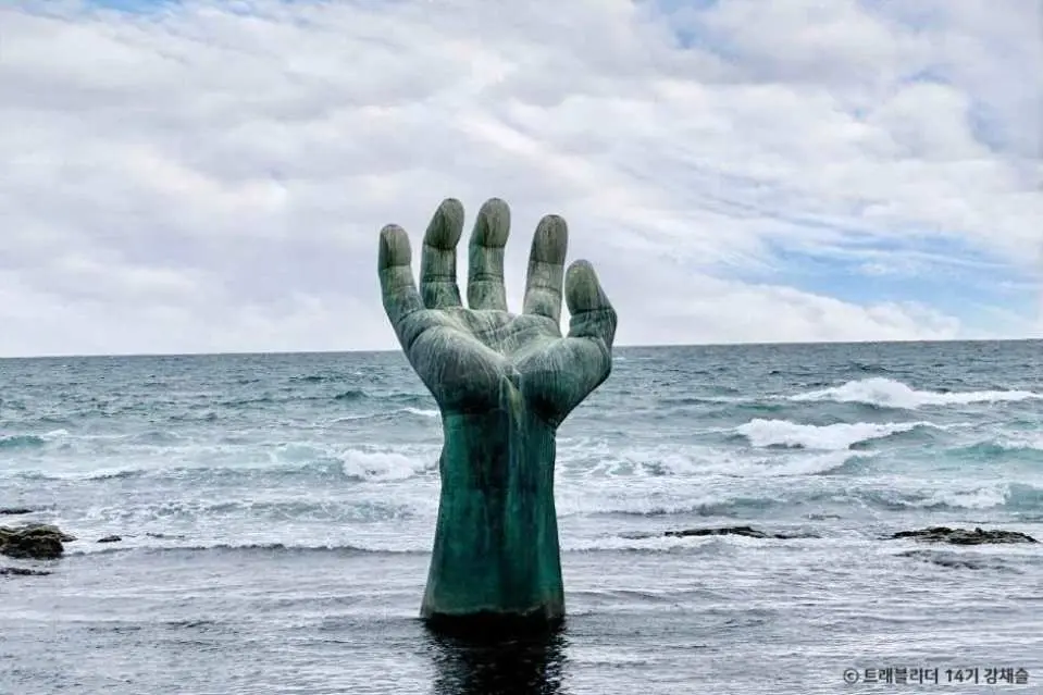 The iconic Hand of Coexistence sculpture at Homigot in Pohang, South Korea, a giant hand rising dramatically from the blue ocean, symbolizing peace and coexistence, a must-see landmark.