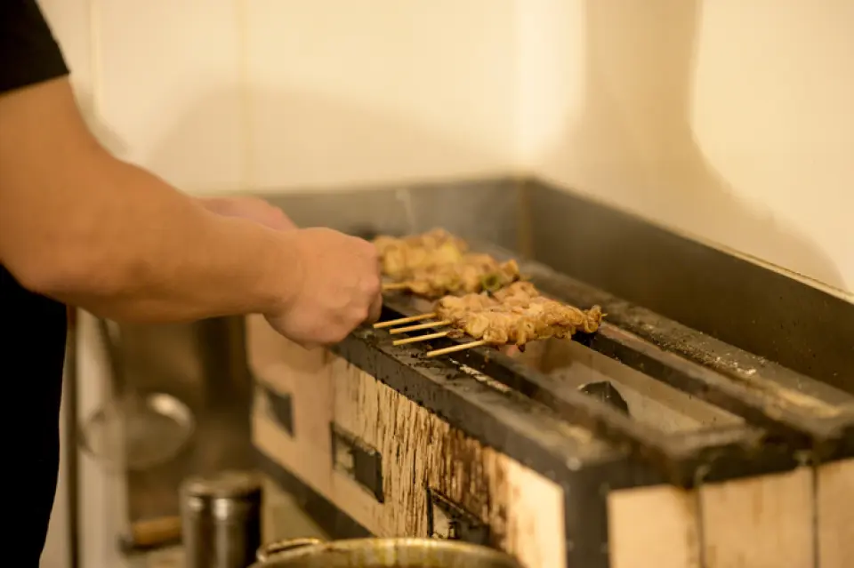 Mỗi xiên thịt đều được xiên thủ công tại cửa hàng, và chúng tôi cam kết đạt được hương vị chỉ có thể có được bằng phương pháp nướng than. Chúng tôi điều chỉnh thời gian nướng mỗi ngày tùy thuộc vào tình trạng của thịt và than. Việc nướng thịt giống như đang quan sát một sinh vật sống, vì chỉ cần lơ là một chút thôi là thịt sẽ cháy, vì vậy chúng tôi không ngừng hoàn thiện kỹ năng của mình. Khi sử dụng than đúng cách, lớp vỏ ngoài sẽ giòn và thơm, trong khi bên trong vẫn mọng nước và mềm. Xiên thịt yakitori của chúng tôi có vẻ lớn hơn mức trung bình, và chúng tôi thường nhận được lời khen về kích thước hấp dẫn của nó. Hãy thưởng thức món yakitori thủ công của chúng tôi, điều mà bạn không thể tìm thấy ở các sản phẩm sản xuất hàng loạt.