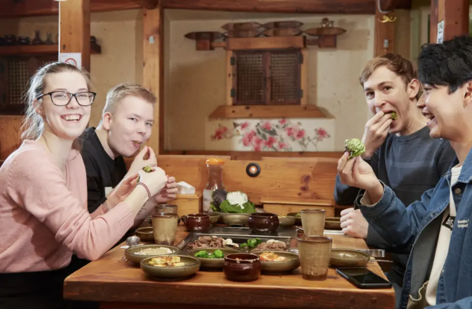 參與首爾小團美食之旅的旅客們，在傳統韓屋風格餐廳裡，開心享用熱騰騰的韓國燒烤與豐富小菜。