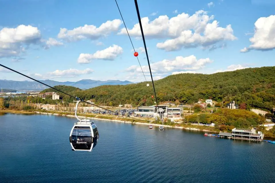 The Samaksan Cable Car slowly glides over the lake, offering passengers stunning views of the lakeside scenery and lush green mountains from inside the cabin, providing a magnificent aerial perspective of Chuncheon.