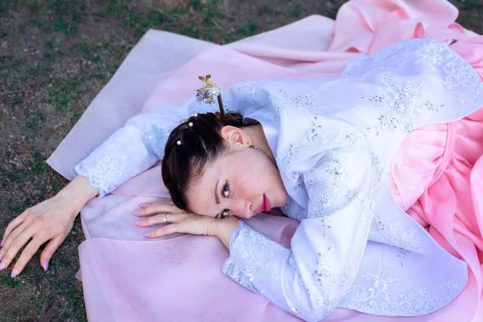 一位女性穿著優雅的韓服側臥於景福宮草地上，享受私人韓劇風格拍攝，展現韓國傳統服飾的柔美氣質。