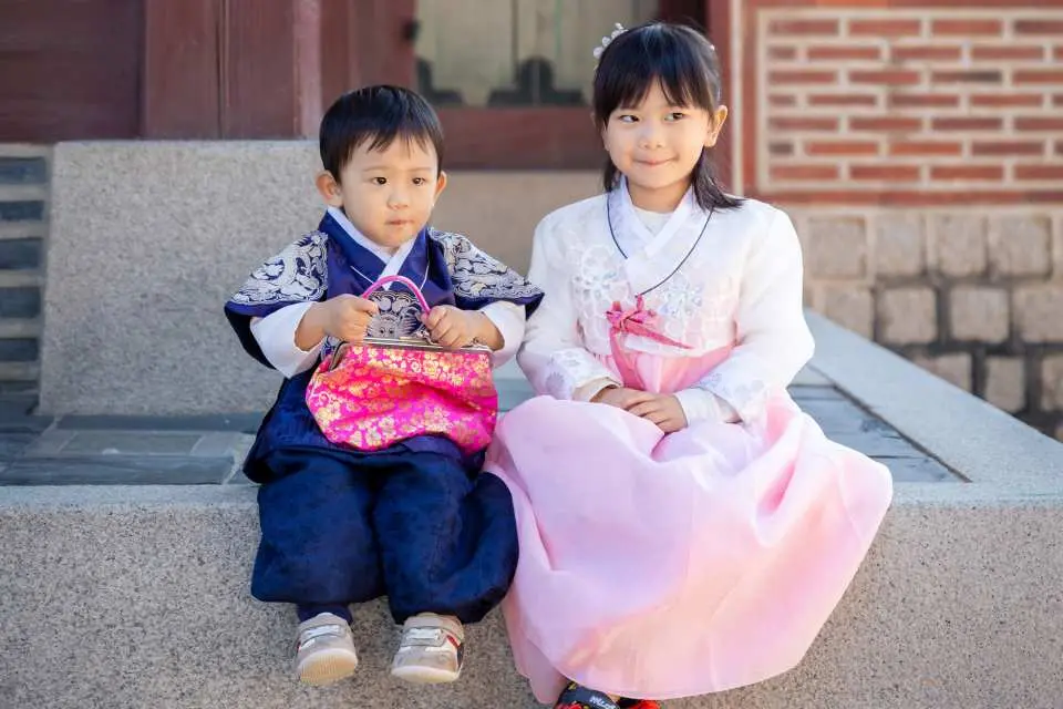 兩位穿著精緻韓服的可愛小孩在景福宮石階上合影，體驗親子韓服拍攝，展現韓國傳統服飾的獨特魅力。