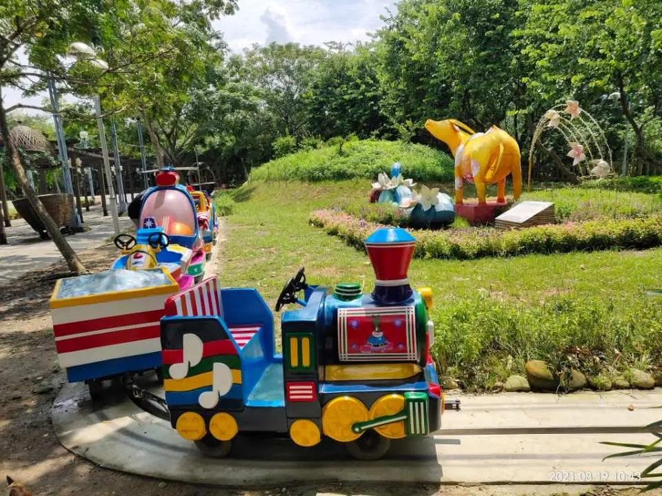 南投竹山文化園區戶外兒童遊樂區的小火車設施，背景有大型黃色動物竹編藝術品，是家庭親子體驗的熱門景點。