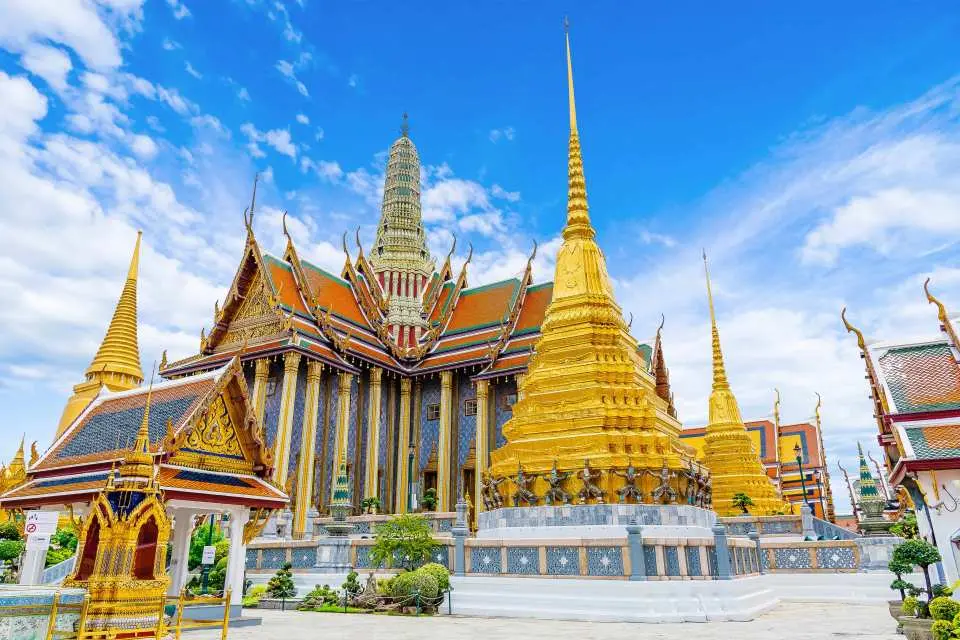 The majestic Grand Palace complex in Bangkok, with golden stupas and exquisite temples shining under a clear blue sky, a must-visit for exploring Thai culture.