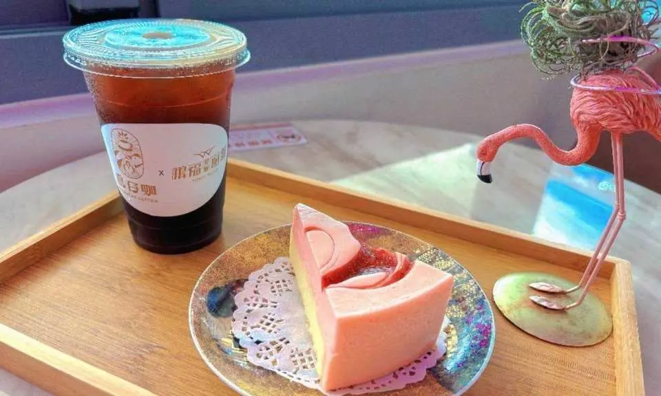 Enjoy a leisurely afternoon tea at Dapeng Bay's secret 'Niaozai Cafe,' featuring an exquisite pink cake and special beverage, complemented by a charming flamingo ornament.