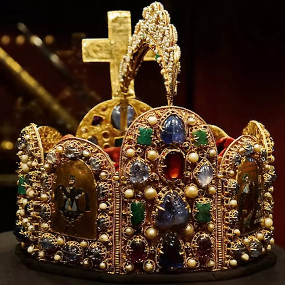 ウィーンの帝国宝物館に展示されている、神聖ローマ帝国の帝冠の華麗なクローズアップ。金色の冠には様々な宝石と真珠が嵌め込まれ、頂上には十字架があり、その宗教的・歴史的意義を示しています。