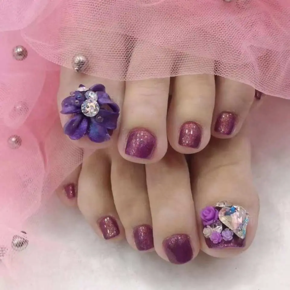 Luxurious pedicure service at Candy Nails in Puchong, featuring glamorous purple nail polish adorned with 3D flowers and sparkling rhinestones for custom nail art.