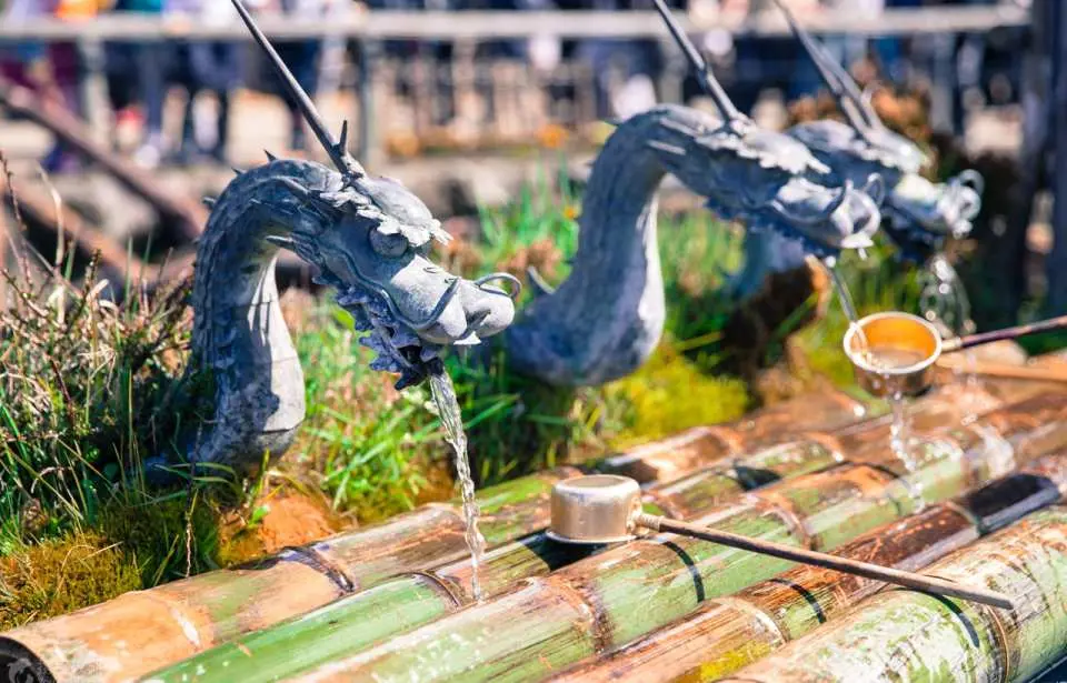 Các vòi nước hình đầu rồng truyền thống tại chōzuya của một ngôi đền Nhật Bản, với nước trong vắt chảy vào ống tre để thanh tẩy nghi lễ.