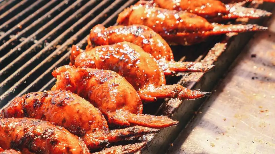 대만 야시장 음식점에서 양념이 잘 배어 노릇하게 구워진 맛있는 닭 날개들이 뜨거운 그릴 위에서 구워지고 있습니다.