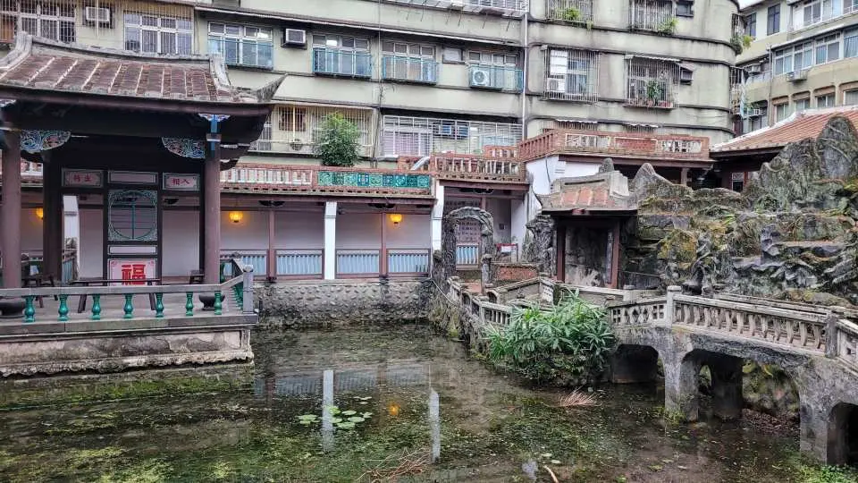 임가화원 고요한 전통 중국 정원 연못. 정교한 돌다리와 고전적인 건축 요소가 고요한 수면에 비치며 평화로운 휴식처를 제공합니다.